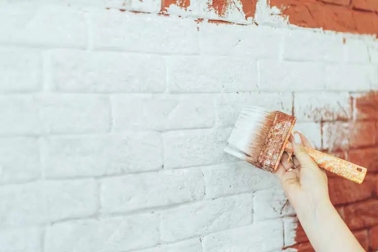 white-limewash-being-applied-to-brick-with-a-brush